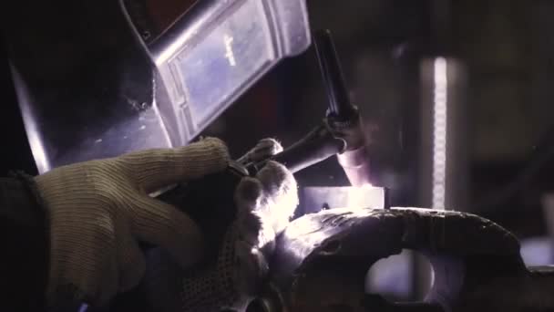 Close-up de uma máscara de soldadores durante a soldagem. Clipe. Soldador solda as partes da estrutura — Vídeo de Stock