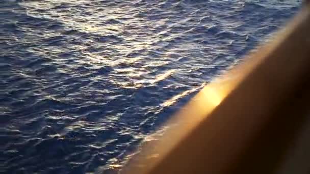 Beautiful dark blue water of the sea and the blurred edge of the yacht. Stock. Ripple in the sea with the sun glare on water surface and the edge of brown yacht deck. — Stock Video