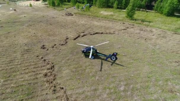 Helicopter hovering over field. Helicopter landed on the field near the forest belt. Helicopter landed on yellow grass, cloudy day — Stock Video