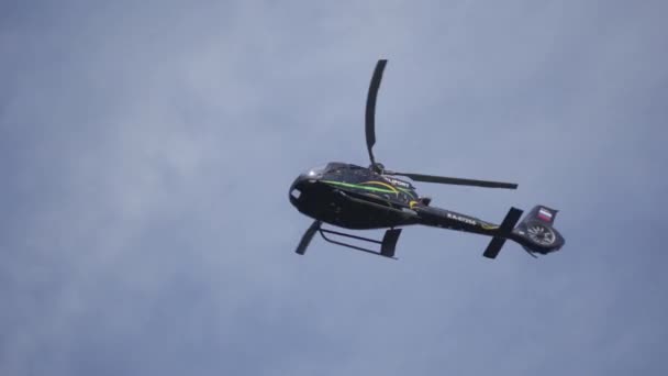 Helicóptero no céu nublado com um raio. Helicóptero de baixo voando através do céu nublado. Helicóptero pairando contra o céu ensolarado e nublado — Vídeo de Stock