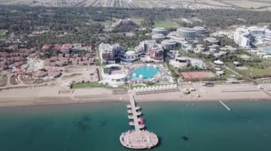 Hotel mavi deniz kıyısında. Video. Beyaz kum, güzel plaj, uzun palmiye ağaçları. Okyanus kıyısında tatil. Havadan görünümü