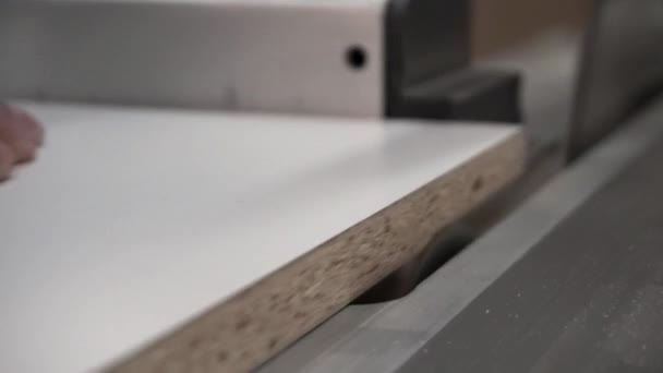 ワーク ショップで木製まな板の円の鋸を使用して大工のクローズ アップ。映像。男性ワーカーがのこぎりで板の端をトリムします。. — ストック動画