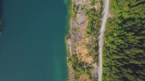 Estrada aérea incrível drone tiro ao longo de um lago. Clipe. Lagoa e estrada em montanhas vista superior — Vídeo de Stock