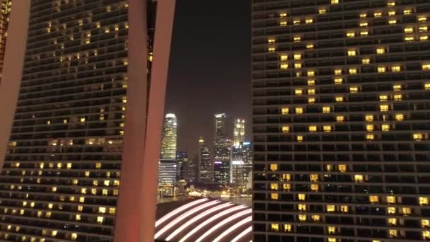 Vista nocturna del horizonte de Singapur volando sobre Marina Bay Sands Hotel. Le dispararon. Vistas aéreas del horizonte de Singapur por la noche — Vídeos de Stock