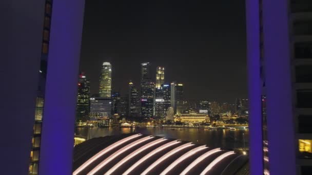 Vista nocturna del horizonte de Singapur volando sobre Marina Bay Sands Hotel. Le dispararon. Vistas aéreas del horizonte de Singapur por la noche — Vídeo de stock