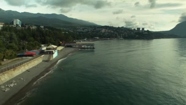 Vista aérea: Mar, praia, mar, cidade resort de Feodosiya, Crimeia. Atingido. Praia da vista aérea turistas relaxar e nadar, vista da cidade — Vídeo de Stock