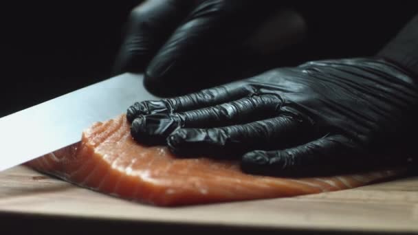 Close-up van sushi chef-kok in handschoenen plakjes verse zalm bij sushibar. Zalmfilets snijden — Stockvideo
