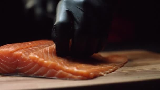 Primer plano del chef de sushi en guantes rebanadas de salmón fresco en el bar de sushi. Cortar filetes de salmón — Vídeos de Stock