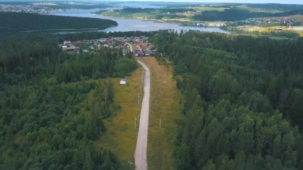 Aerial byvägen genom skogen och fälten. Klipp. Vägen som leder genom skogen i byn. Flygfoto — Stockvideo