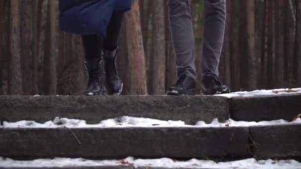 Νεαρό ζευγάρι τρέχει κάτω από τις σκάλες στο χειμερινό πάρκο. Clouse-up ζευγάρια ποδιών. — Αρχείο Βίντεο
