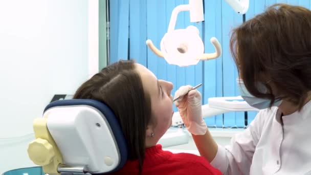 Mujer en el dentista mientras el proceso de tratamiento en la clínica dental, el trabajo del estomatólogo con el paciente. Dentista y paciente en consultorio odontológico, concepto de medicina . — Vídeo de stock