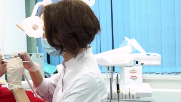 Mujer dentista arreglando dientes femeninos jóvenes en el consultorio dental. Ocupado odontólogo en el trabajo, concepto de cuidado dental . — Vídeo de stock