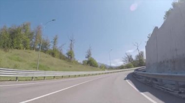 Beyaz taş bariyer ile yüksek hızlı bir yolu boyunca mavi berrak gökyüzü karşı bir taraftan yaz aylarında acele araba yoldan görüntüleyin. Sahne. Araba ile seyahat.