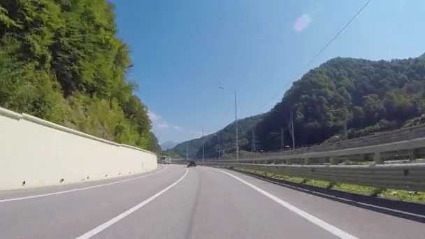 Vue de la voiture se déplaçant sur une autoroute à Krasnaya Polyana contre le ciel bleu, les arbres et les montagnes du Caucase en été. Scène. Sotchi, Russie . — Video