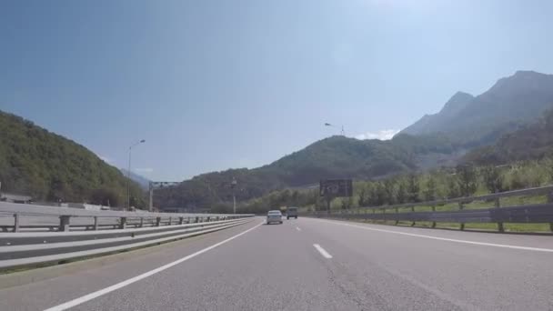 Visa på en väg till berget olympiska byn från rörliga bil med hög och gamla bergen i bakgrunden mot blå himmel. Scen. Vacker och solig dag. — Stockvideo