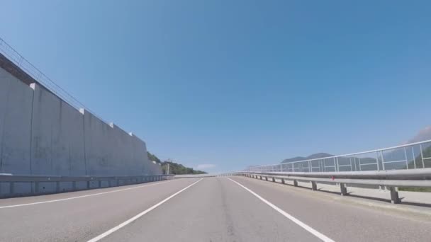 Uitzicht vanaf de auto draaien links op een snelweg onder de kabelbaan op de achtergrond van de prachtige bergen, vallende bomen en struiken. Scène. Prachtige zomer reis. — Stockvideo