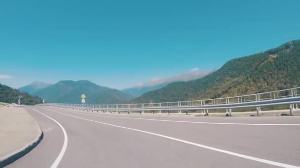 在蓝色的天空下行驶的汽车上, 可以看到道路和被树木覆盖的山脉的风景如画的景色。现场。山风景. — 图库视频影像