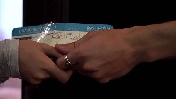 Close up for loving couple hands giving air tickets and stroking fingers. Man hands passing plane tickets to a woman hands with tenderness, side view. — Stock Photo, Image