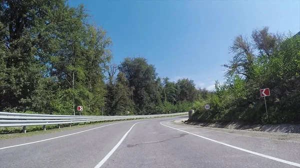 Déplacement vers l'avant de la voiture sur l'autoroute serpentine, entouré de collines boisées, vue du conducteur. Scène. Perspective à la première personne de la route depuis le véhicule . — Photo