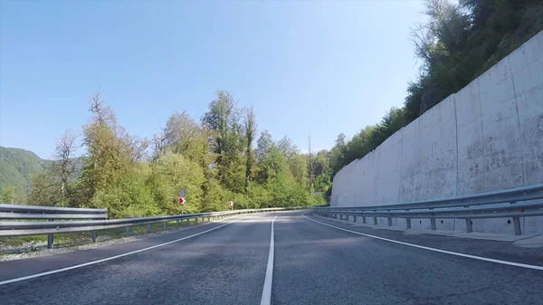 Vorwärtsbewegung des Autos auf Serpentinenautobahn, umgeben von bewaldeten Hügeln, Fahrersicht. Szene. Ich-Perspektive auf die Straße vom fahrenden Fahrzeug aus. — Stockfoto