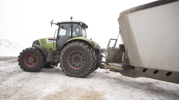 Close up for moving tractor with trailer at the farm in winter, agriculture concept. Footage. Agricultural machinery, tractor driving on snow.