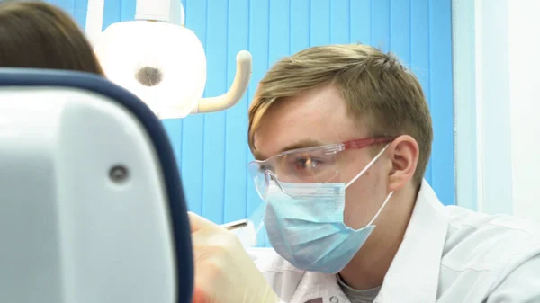 Close-up voor jonge dokter in beschermend masker houden van tandarts instrumenten op de tandheelkundige kliniek, geneeskunde concept. Tandarts controle van de tanden van de patiënt zittend in een stoel. — Stockfoto