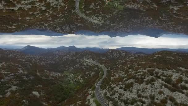 Luchtfoto van vele hoge bergen en de weg, horizon spiegeleffect. Mooi landschap met rotsen en de weg op bewolkte hemel pagina, aanvang thema. — Stockvideo