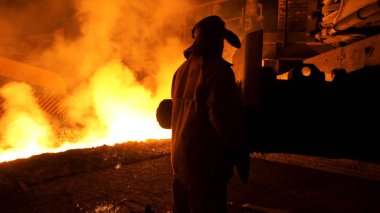 Sıcak erimiş metal kontrollü çelik fabrikasında koruyucu üniforma Metalurji işçisi döküm süreci. Ağır sektörde çalışan adam.