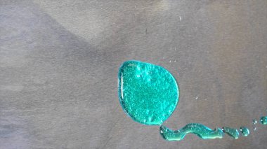 Gri metal arka planda büyük turkuaz lekenin üst görünümü stil tutarak. Metal levha yüzeyinde parlayan parçacıklar ile parlak deniz mavisi boya büyük damla.