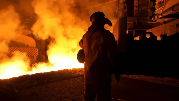 Lavoratore metallurgico in uniforme protettiva presso l'acciaieria che controlla il processo di colata dei metalli fusi a caldo. Uomo che lavora nell'industria pesante . — Foto Stock