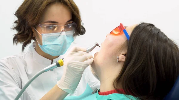 Close-up voor een vrouw tandarts de behandeling van vrouwelijke patiënt, geneeskunde concept. Vrouw tandarts in uniform met tandheelkundige apparatuur tijdens het werkproces. — Stockfoto