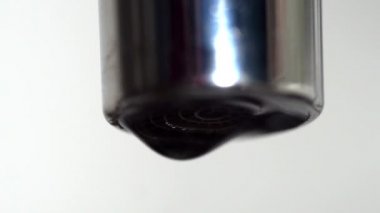 Yakın çekim delik dokunun damlayan su. Medya. Su beyaz izole arka planda kötü kapalı musluk gelen sopa ve damla damla