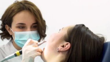 Diş çürük önleme, tıp konsepti gerçekleştiren genç dişçi kadın için yakın. Klinikte Diş ameliyatı sırasında dişçi sandalyesinde kadın.