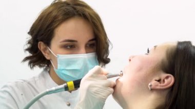 Kadın hasta, tıp konsepti tedavisinde bir kadın diş doktoru için yakın. Çalışma sürecinde Dental ekipmanlarla üniformalı kadın dişçi.