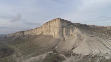 Mavi gökyüzüne karşı yeşil ova ve yollarda yakın yüksek gri dağ üzerinde alt görünüm. Atış. Kırsal dağ manzara.