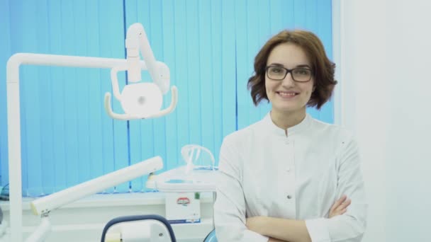 Kadın dişçi gülümseyen istemci karşılamaktadır. Medya. Beyaz önlük kadın dişçi diş ofiste yeni müşteri ağırlıyor. Diş kavramı — Stok video