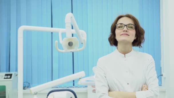 Mujer dentista se encuentra con el cliente sonriendo. Medios. Mujer dentista en bata blanca da la bienvenida a un nuevo cliente en el consultorio dental. Concepto dental — Vídeo de stock