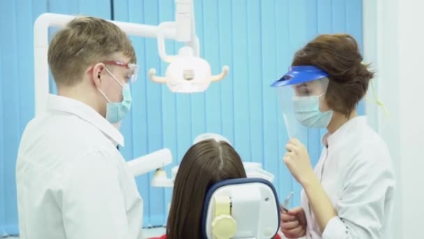 Dentistas homens e mulheres com máscaras e óculos. Mídia. Parceiros dentistas em uniforme estéril de proteção com equipamento pronto para começar a trabalhar — Vídeo de Stock