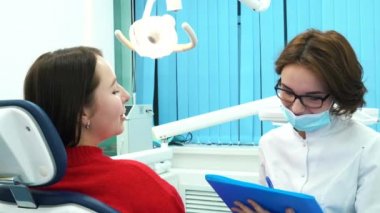 Genç bayan hasta ve onun diş hekimi ile tedavi bir müzakeresi tartışırken mavi klasör close-up. Diş Bakımı.