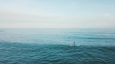 Havadan görünümü açık turkuaz deniz suyu mavi gökyüzü karşı kürek gemide Yüzme genç adam. Hisse senedi. Resort sezon.