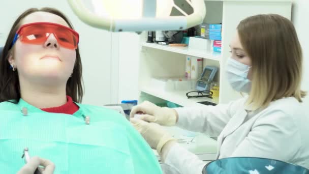 Tandläkaren arbetar med assistent. Media. Assistent ger nödvändiga läkemedel eller verktyg till tandläkare under behandling av patienten — Stockvideo