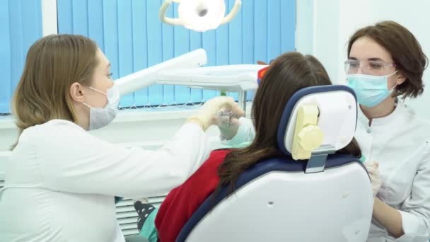 Trabajo de dentista y asistente. Medios. Asistente dental le da herramientas durante el procedimiento de tratamiento dental del paciente — Vídeos de Stock