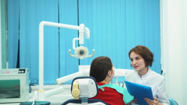 Крупним планом молода жінка-помічник позує на передньому плані стоматолога і її пацієнта. Стоматологічна команда . — стокове відео