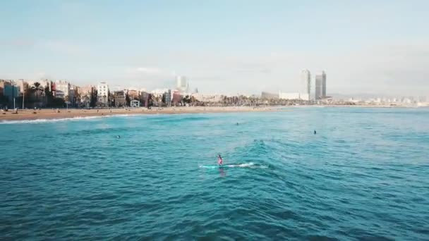 Veduta dell'uomo che galleggia su pedana in acque cristalline turchesi contro il cielo blu e la costa sullo sfondo. Azioni. Stagione balneare . — Video Stock