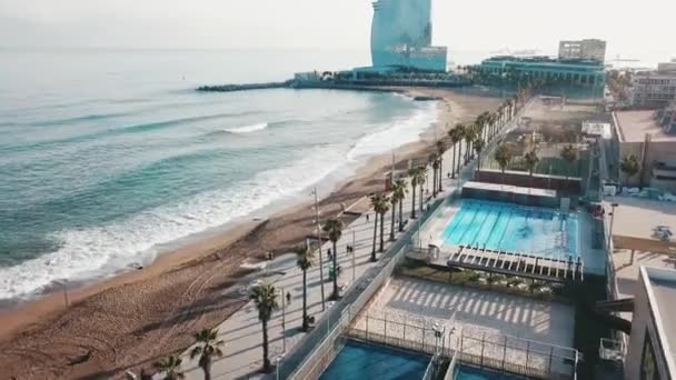Luchtfoto van de prachtige kustlijn, de moderne gebouwen, het zwembad en de mensen lopen op een strand tegen blauwe hemel. Voorraad. Resort seizoen. — Stockvideo