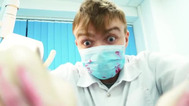 Close-up of crazy dentist at work with a protective mask stained with blood. Bloody psychopath. — Stock Video