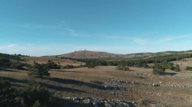 Mavi gökyüzü ve bulutlar karşı yeşil tepeler ile güzel iğne yapraklı ağaçlar. Vurdu. Fütüristik binaları ile bir tepede görüntülemek