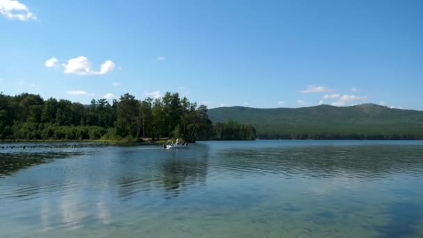 Los amantes viajan en un bote en un lago. Amigos juntos relajándose en el agua. La hermosa naturaleza alrededor — Vídeos de Stock