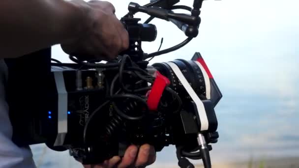 Hombre sosteniendo una cámara filmando una película en el bosque. Cámara costosa para la película en el bosque — Vídeos de Stock