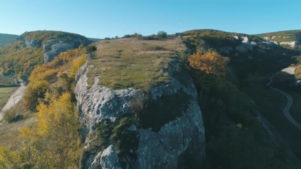 Na vrcholu útesu. Střela. Krásná krajina s obrovským skalnaté útesy, zelené trávy a kameny proti modré obloze — Stock video